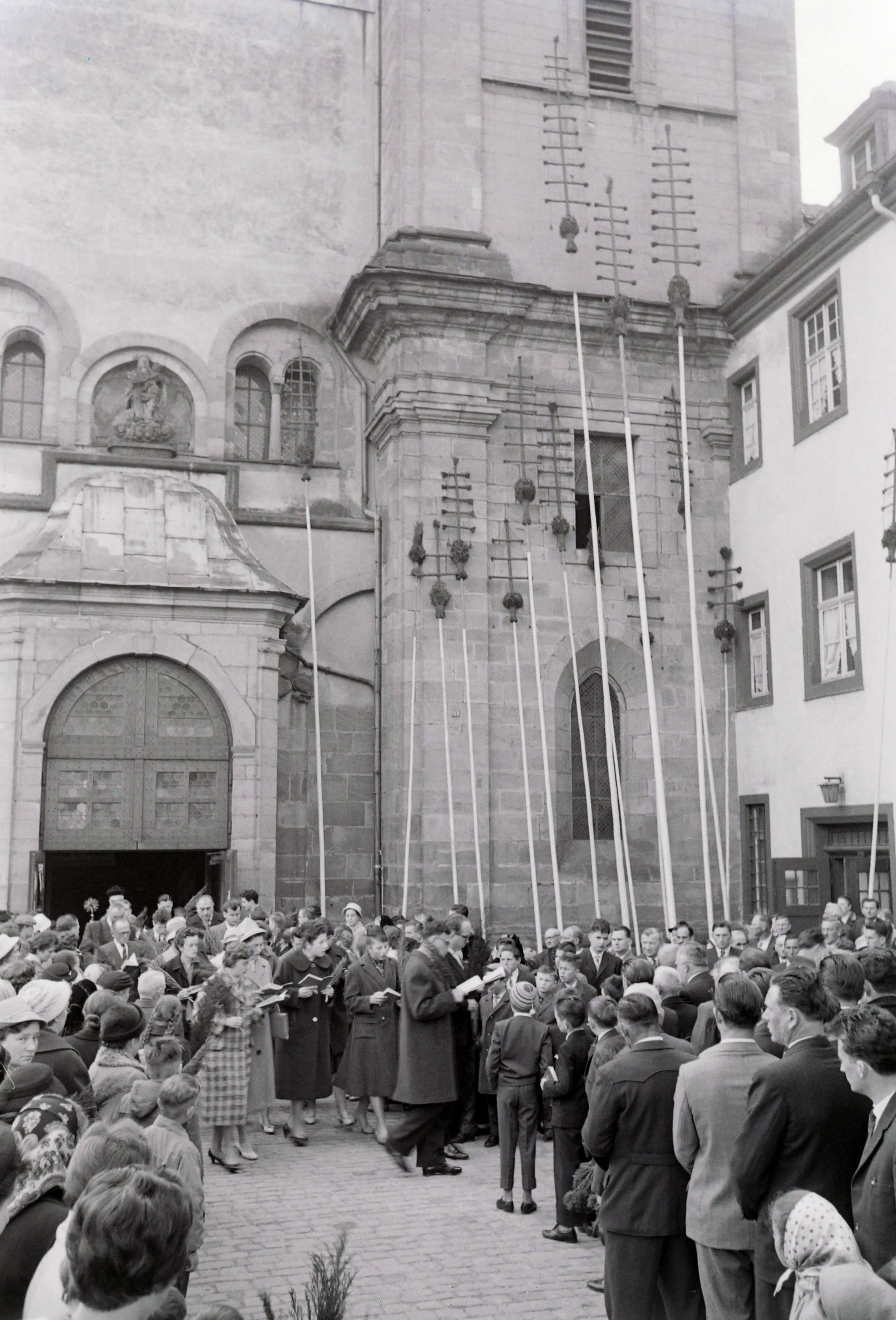 Die langen Palm-Stangen lehnen an der Aussenfassade der Kirche, ein Chor singt