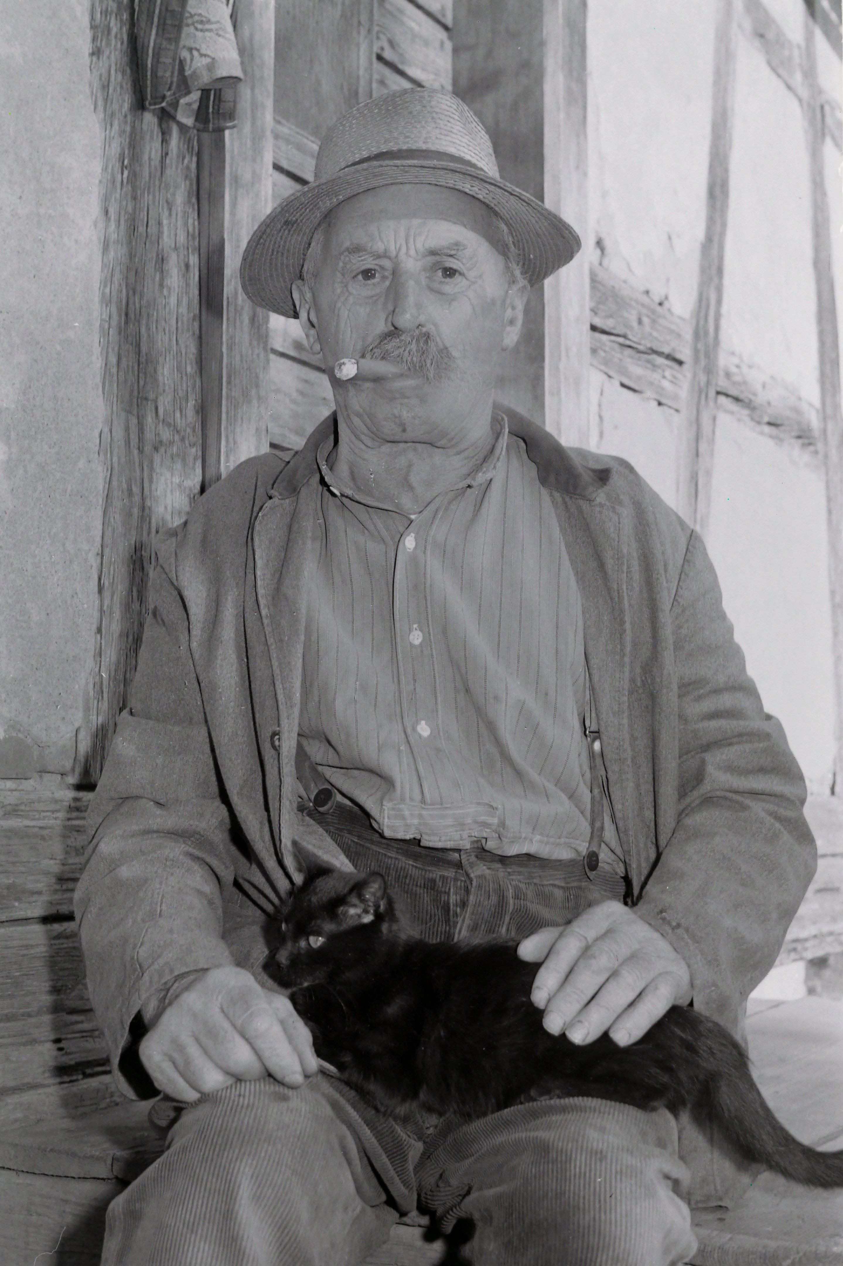 Aufnahme vom 30.09.1970, ein älterer Mann sitzt Zigarre rauchend da, mit einer Katze auf dem Schoss. Bild von Friedrich Strohm 