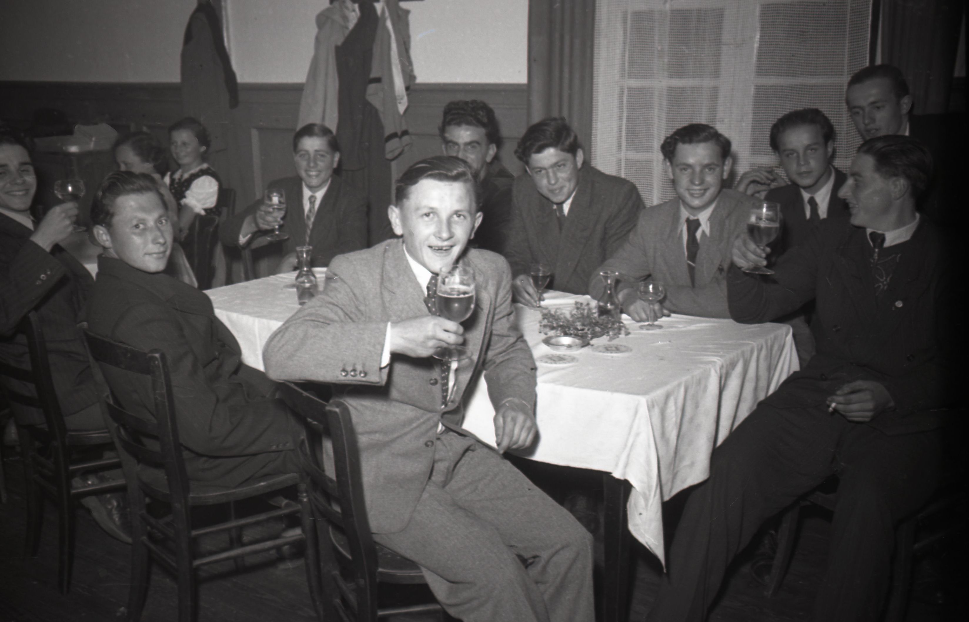 Junge Männer am Tisch heben das Glas