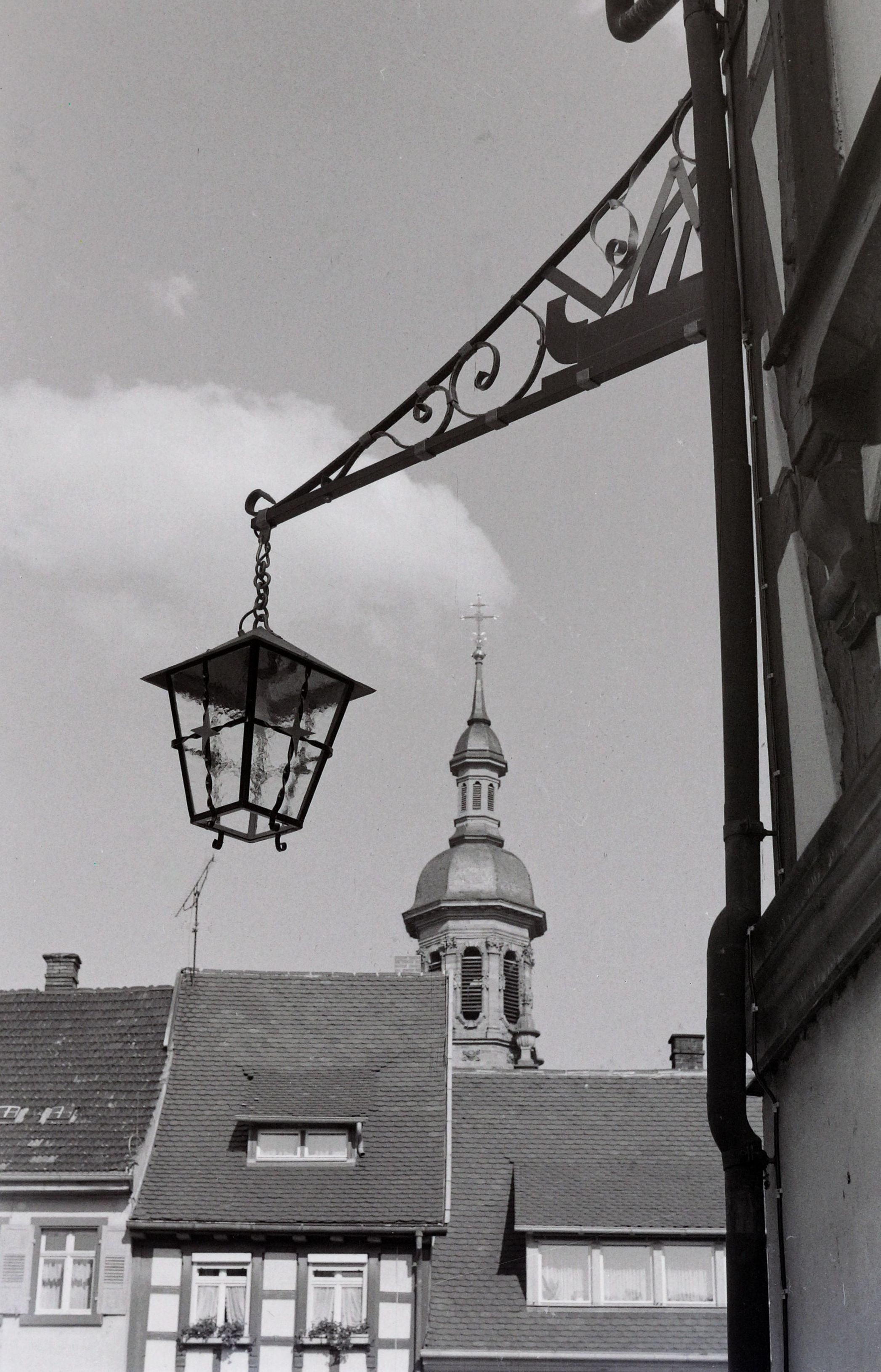 Blick auf eine neue Lampe mit Schreiner-Emplem verbunden und im Hintergrund der Kirchturm von St. Marien- Stadtkirche